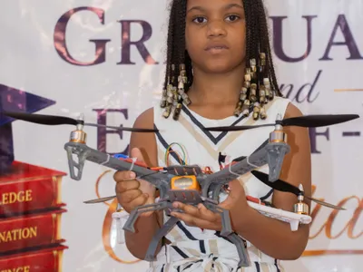 A BRIF student holds a quadcopter drone she built as part of a school technology project.