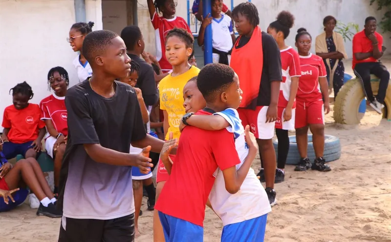 Two BRIF students share a warm hug on the playground, surrounded by classmates.